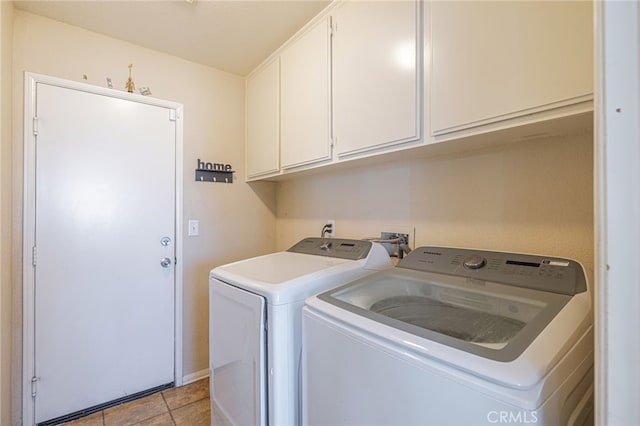 laundry area with washing machine and clothes dryer, light tile patterned floors, and cabinets