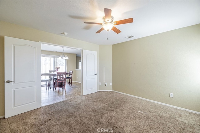 carpeted spare room with ceiling fan with notable chandelier