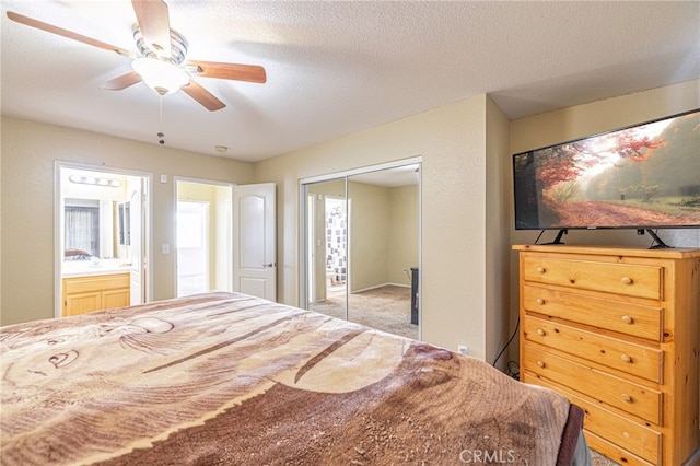 bedroom with a closet, ceiling fan, connected bathroom, and a textured ceiling