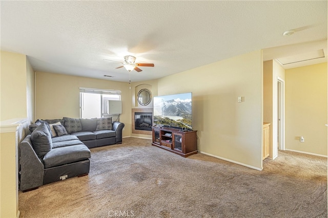 carpeted living room featuring ceiling fan and a textured ceiling