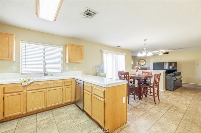 kitchen with dishwasher, tile counters, decorative light fixtures, sink, and kitchen peninsula