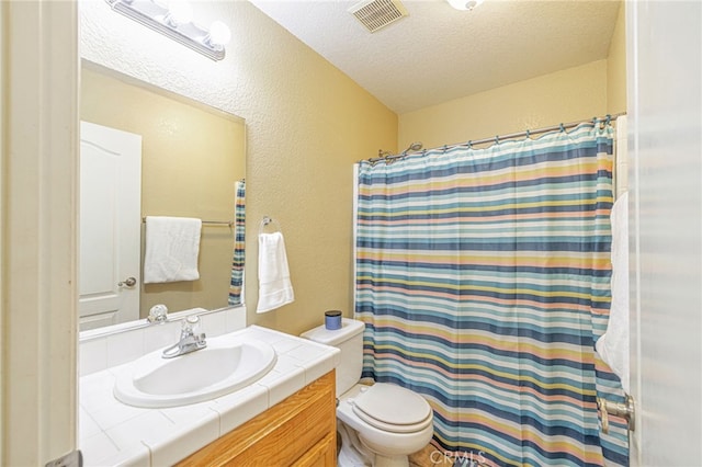 bathroom featuring a textured ceiling, toilet, and vanity