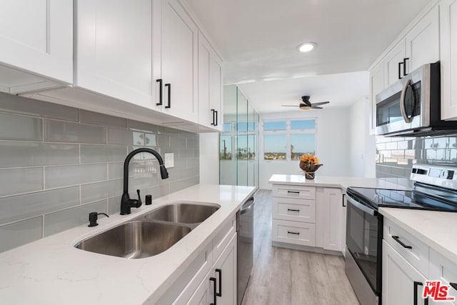 kitchen featuring sink, light hardwood / wood-style flooring, appliances with stainless steel finishes, light stone countertops, and white cabinets