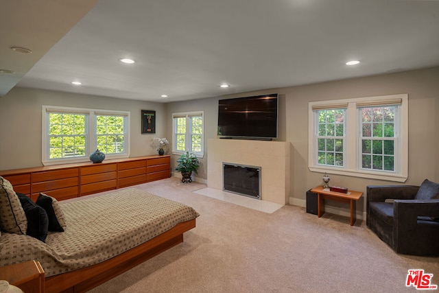 carpeted bedroom with a tiled fireplace and multiple windows