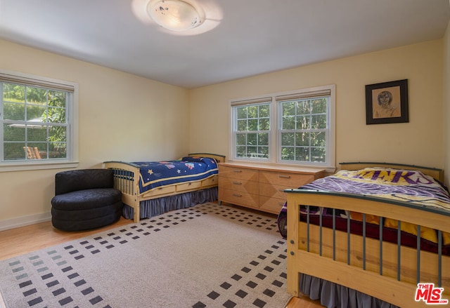 bedroom with light hardwood / wood-style floors and multiple windows