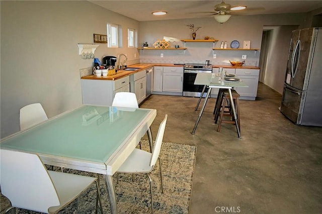 kitchen with wood counters, white cabinetry, sink, ceiling fan, and stainless steel appliances