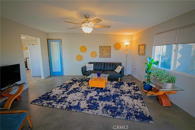 living room featuring ceiling fan and concrete flooring