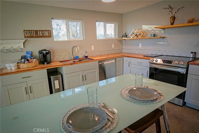 kitchen with butcher block countertops, sink, white cabinets, and appliances with stainless steel finishes