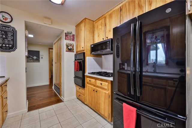 kitchen with light tile patterned flooring, backsplash, and black appliances