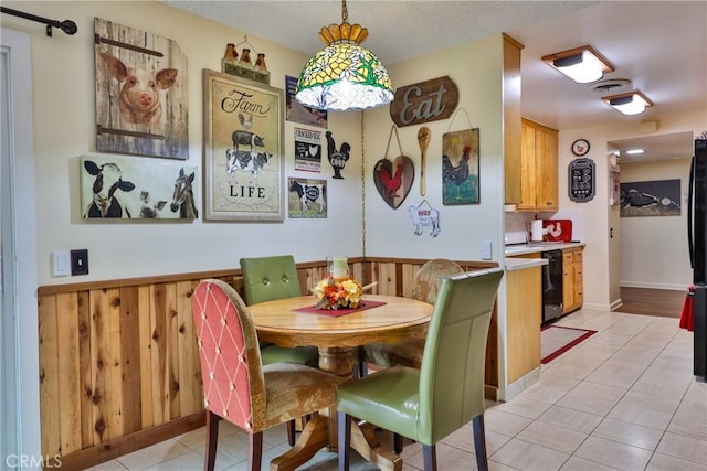 tiled dining room featuring wood walls