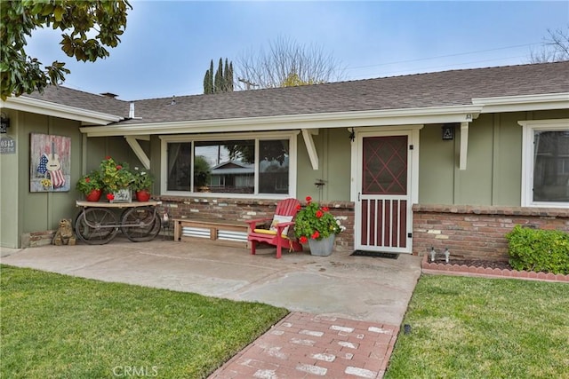 view of exterior entry featuring a yard and a patio area