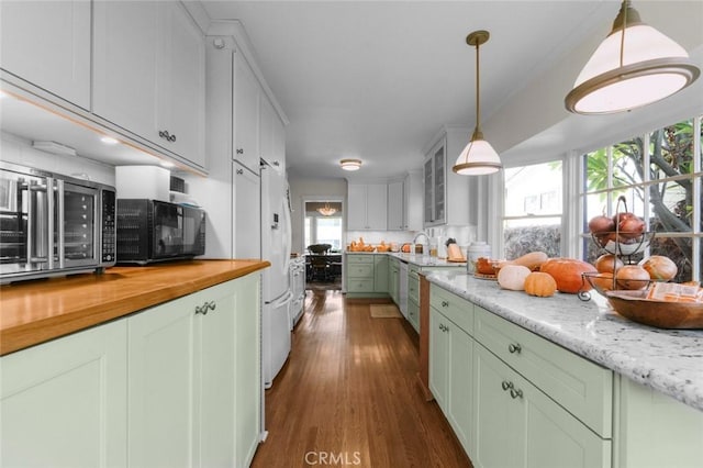 kitchen with sink, dark wood-type flooring, green cabinets, hanging light fixtures, and light stone countertops