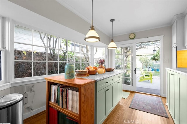 kitchen featuring pendant lighting, ornamental molding, green cabinets, and light wood-type flooring