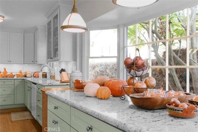 kitchen featuring sink, hanging light fixtures, white dishwasher, light hardwood / wood-style floors, and green cabinetry