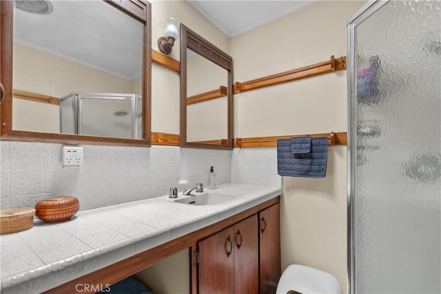 bathroom featuring tasteful backsplash, ornamental molding, an enclosed shower, and vanity