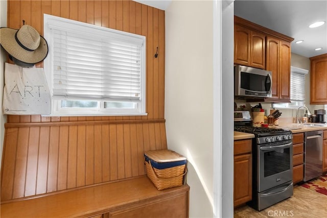 kitchen with stainless steel appliances, plenty of natural light, sink, and wooden walls