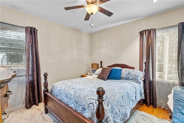 bedroom featuring ceiling fan, light hardwood / wood-style floors, and multiple windows