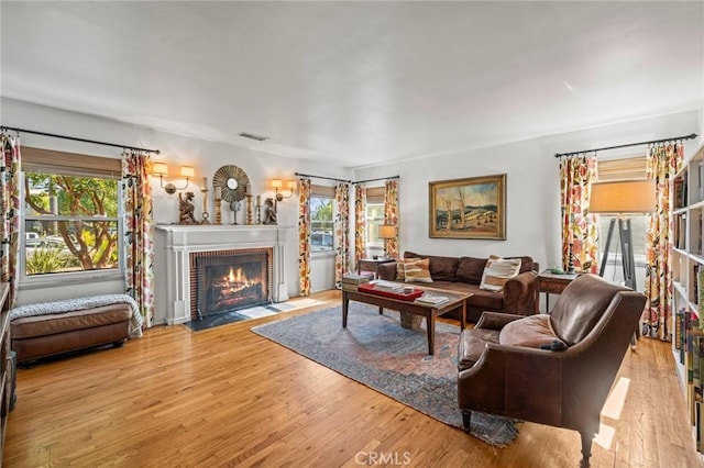 living room with light wood-type flooring and a brick fireplace