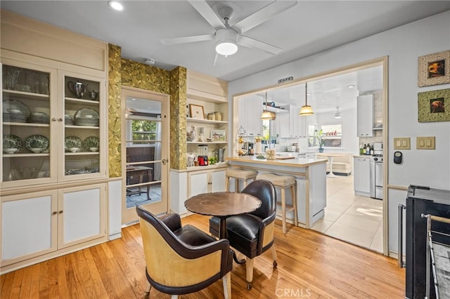 dining space with ceiling fan, light hardwood / wood-style floors, and built in features