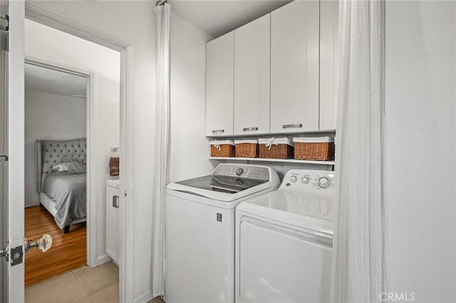 laundry area featuring cabinets, separate washer and dryer, and light tile patterned floors