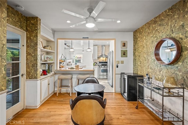 kitchen with white cabinets, wall chimney exhaust hood, stainless steel appliances, built in features, and kitchen peninsula