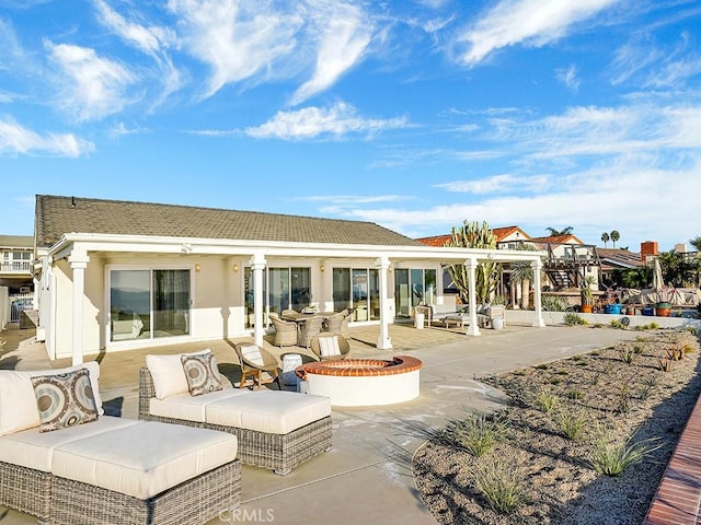 rear view of property featuring a patio and an outdoor fire pit