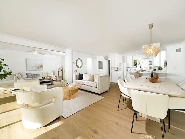 living room with ceiling fan with notable chandelier and light wood-type flooring