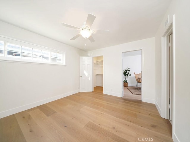 unfurnished bedroom featuring light hardwood / wood-style floors, a spacious closet, ceiling fan, and a closet