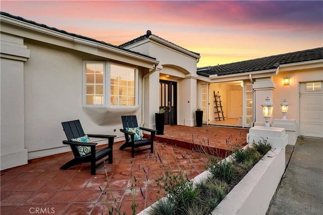 patio terrace at dusk featuring a garage