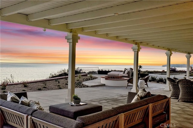 patio terrace at dusk featuring an outdoor living space and a water view