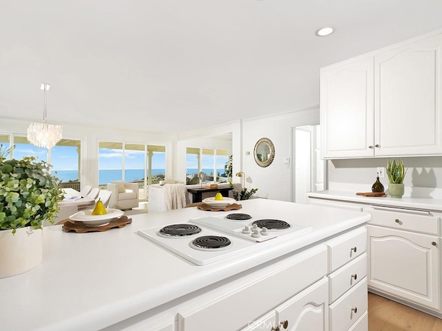 kitchen with white cabinetry, hanging light fixtures, white electric cooktop, and light hardwood / wood-style flooring