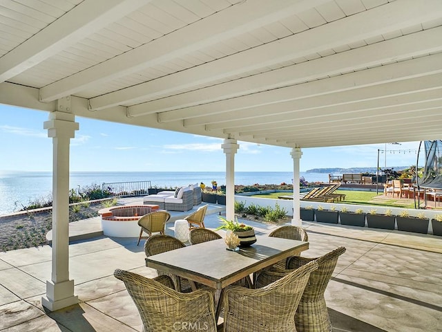 view of patio / terrace featuring a water view and an outdoor living space with a fire pit