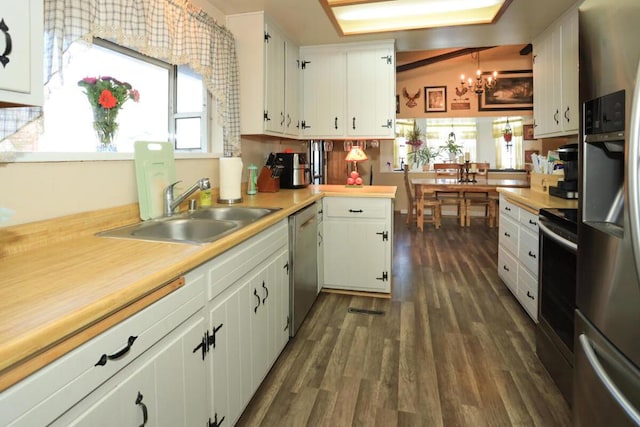 kitchen with pendant lighting, white cabinets, stainless steel appliances, sink, and kitchen peninsula