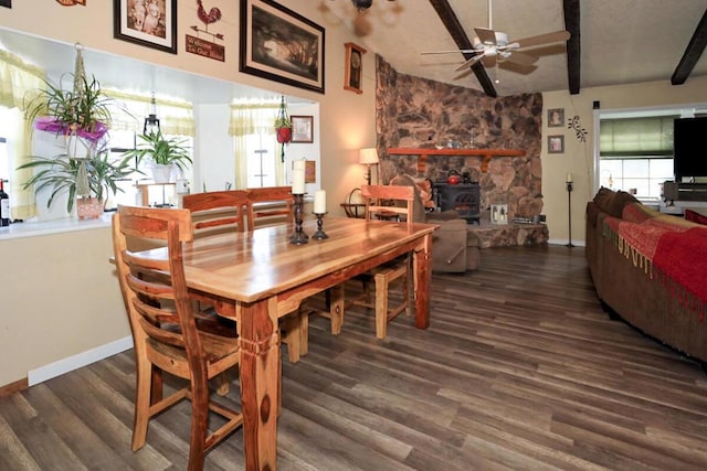 dining space featuring ceiling fan, a wood stove, dark hardwood / wood-style floors, and vaulted ceiling with beams