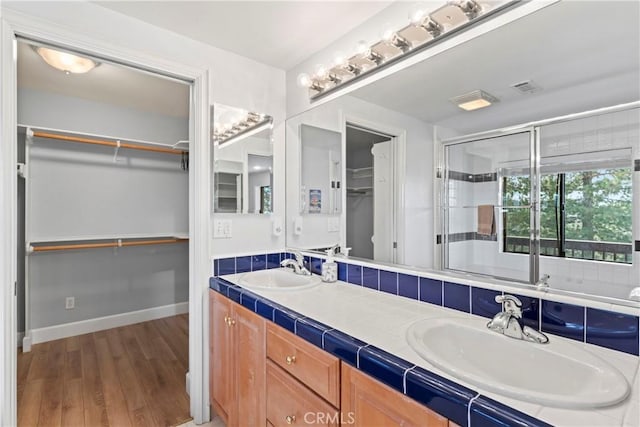 bathroom with hardwood / wood-style flooring, a shower with shower door, and vanity