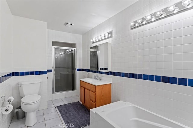 full bathroom featuring plus walk in shower, toilet, tile patterned floors, and tile walls