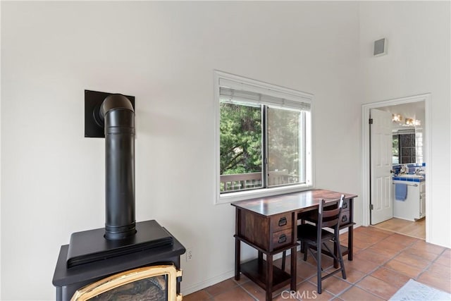 dining area featuring a towering ceiling, tile patterned floors, and a wood stove