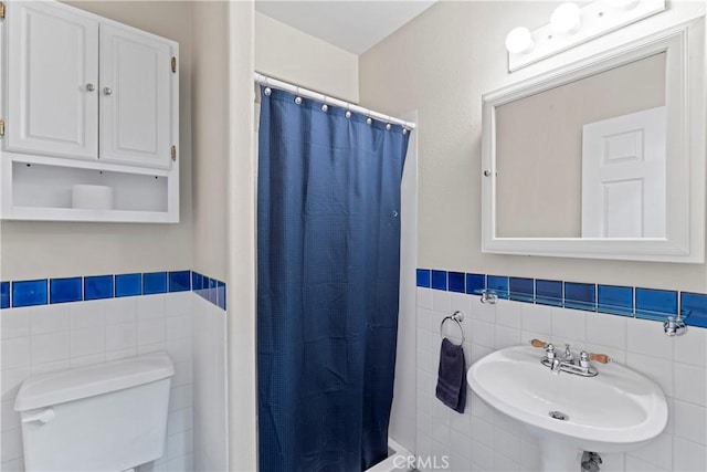 bathroom with sink, curtained shower, toilet, and tile walls