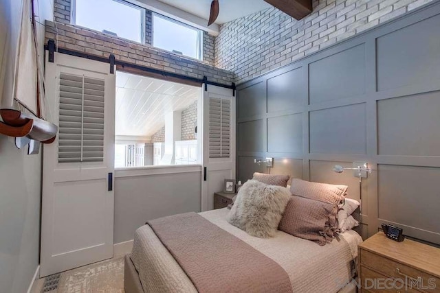 bedroom with brick wall and a barn door