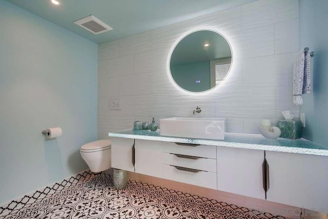 bathroom featuring vanity, tile walls, and toilet