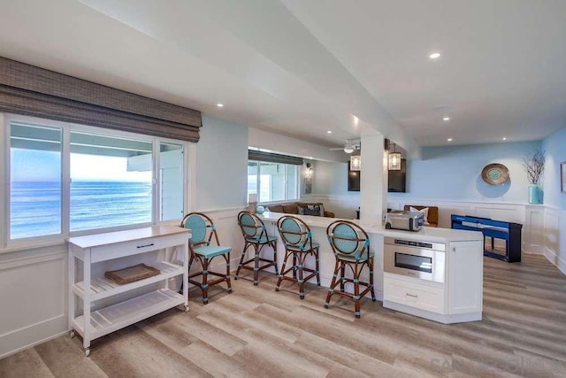 kitchen featuring white cabinetry, light wood-type flooring, kitchen peninsula, and a kitchen bar