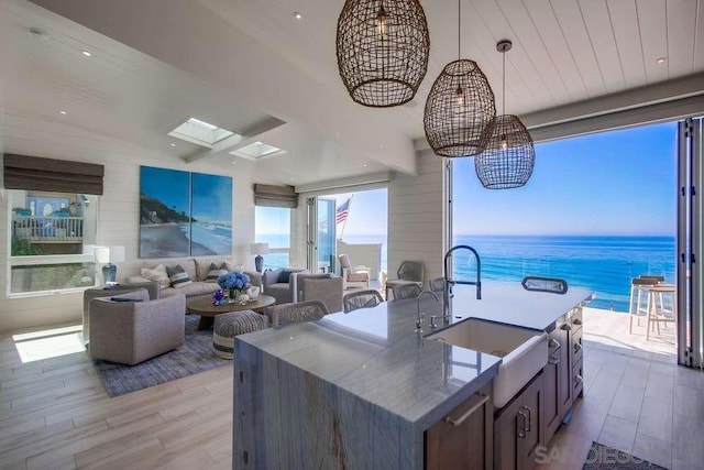 kitchen featuring pendant lighting, a center island with sink, light hardwood / wood-style floors, and a water view