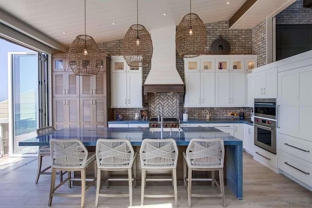 kitchen featuring tasteful backsplash, decorative light fixtures, lofted ceiling, and a spacious island