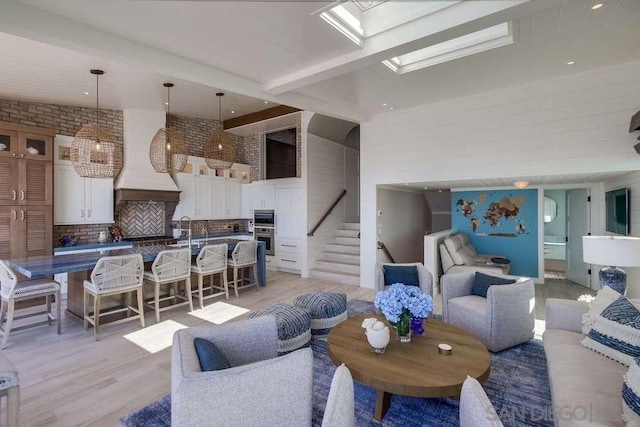 living room with light hardwood / wood-style flooring, lofted ceiling with skylight, and brick wall