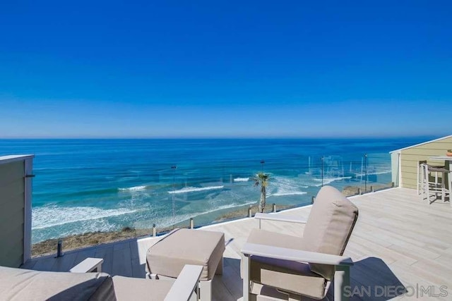 view of patio / terrace featuring a balcony, a water view, and a view of the beach