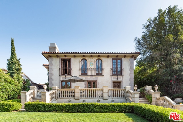 mediterranean / spanish house with a balcony and a front lawn