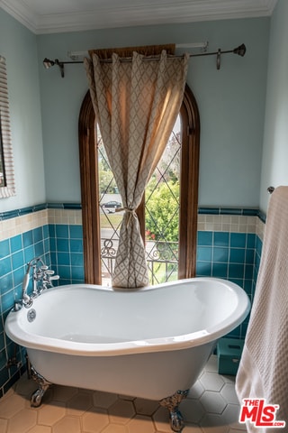 bathroom featuring tile patterned floors, a tub, tile walls, and crown molding