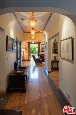 hallway with dark wood-type flooring and ornamental molding