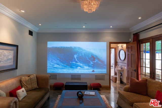 tiled cinema room featuring crown molding, a chandelier, and french doors