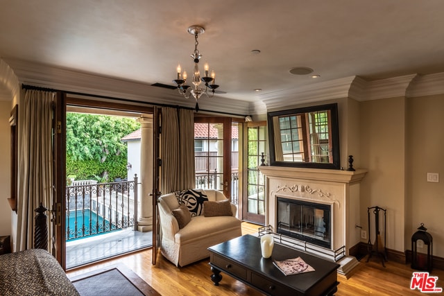 living room with light hardwood / wood-style flooring, crown molding, and an inviting chandelier